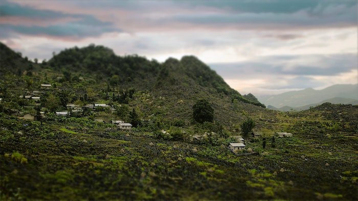 A tilt shift photography shot of a jungle village on a hillside
