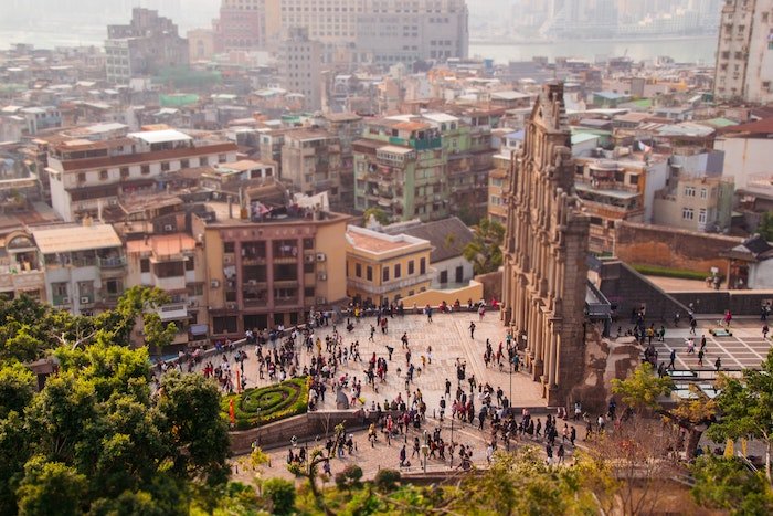 A tilt-shift shot of people standing before a temple