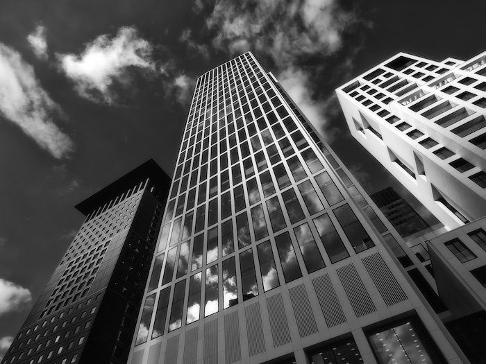 A black and white image of a skyscraper taken from a worm's eye view