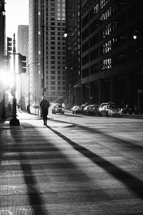 a black and white photo of a city street with long shadows