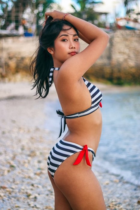 girl in a striped bikini looking over her shoulder as a bikini pose example