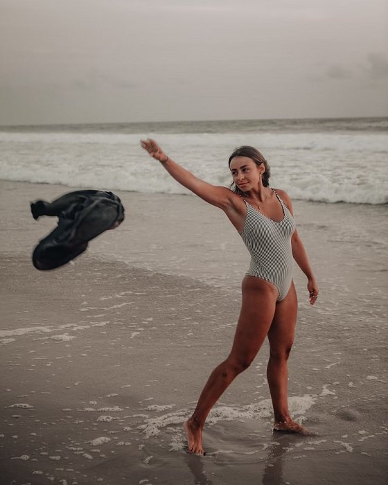 Woman in swimsuit tossing her towel on a beach a bikini pose idea