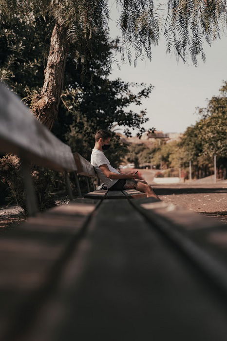 ênfase na fotografia demonstrada pelas linhas principais de um jovem sentado em um banco em um parque