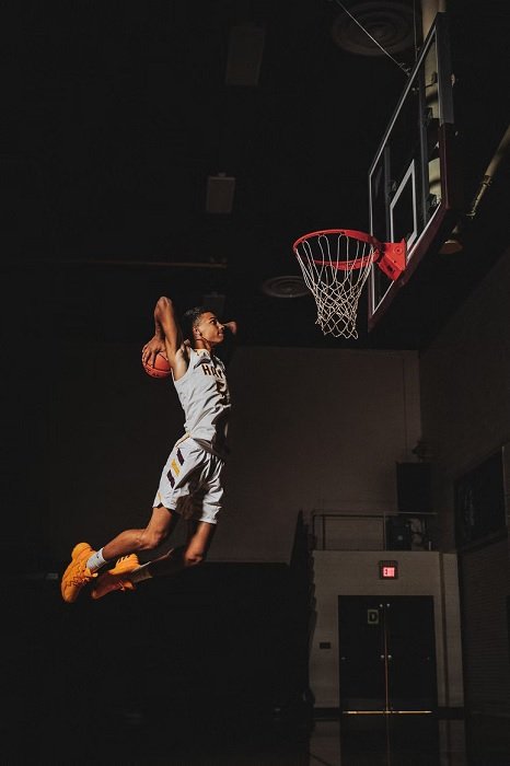 Jovem jogador de basquete pulando para um slam dunk
