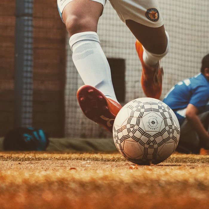 Vista ao nível do solo de uma pessoa chutando uma bola de futebol