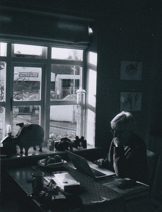 Woman on a computer sitting next to a window shot in black and white