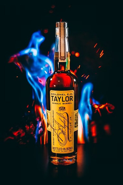 Bottle of whisky with blue flames behind for commercial photography