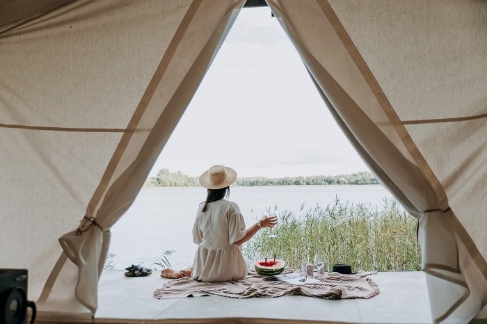 Woman sitting outside a tent next to a lake