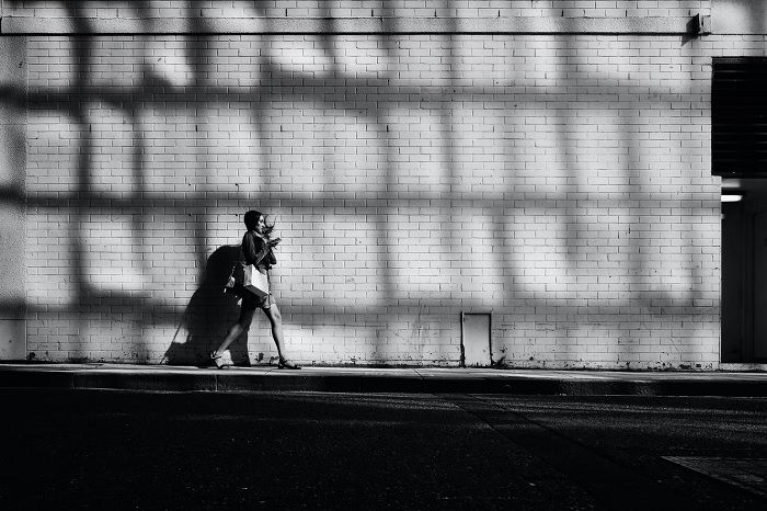 Woman with shopping walking next to a brick wall, as an example of street photography