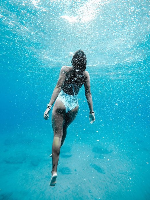 一名女游泳者浮出水面的水下照片