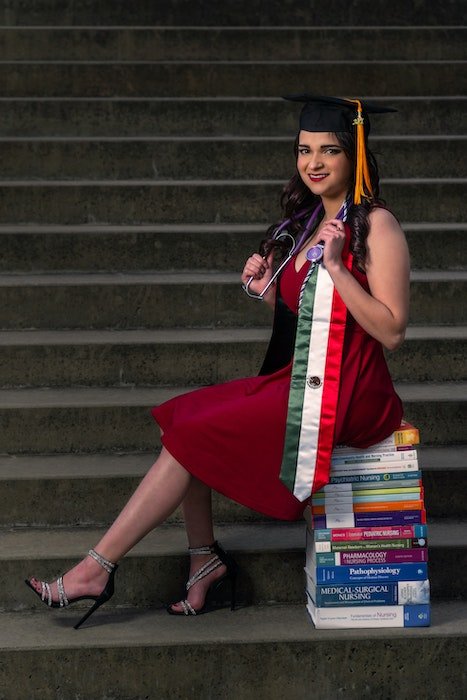 Senior high-school graduate sitting on a stack of books