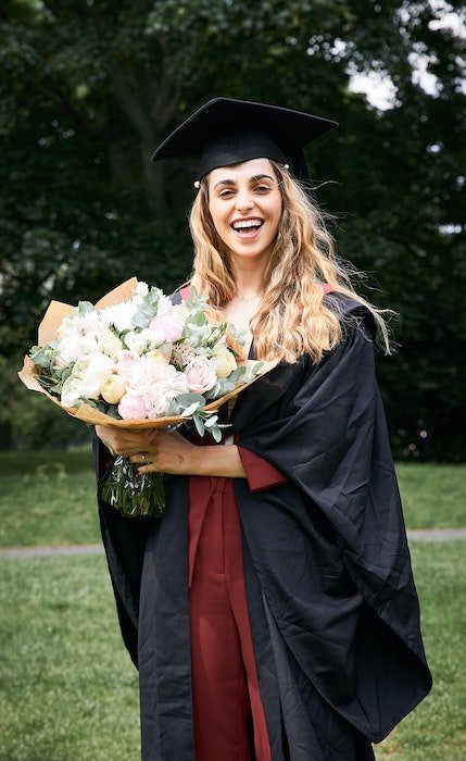 A senior high-school graduate holding a bouquet of flowers