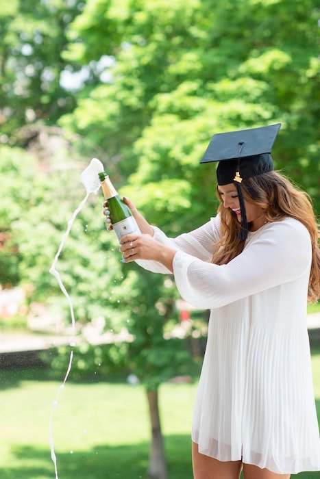 Senior high-school graduate popping a bottle of champagne as a cool senior picture idea