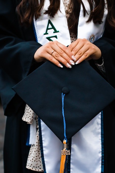 A detail of a graduate holding their grad cap with a 2021 tassel