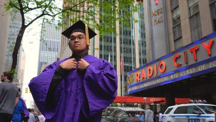 Senior high-school graduate posing in front of Radio City Music Hall in New York City