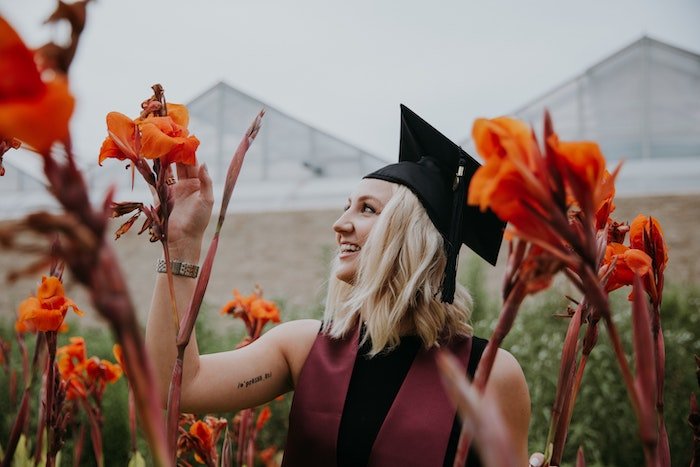 Senior high-school graduate posing in a field of flowers as a senior picture idea