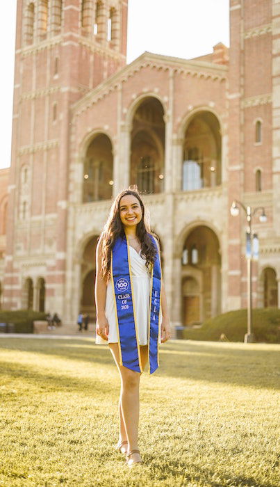 Girl standing in on a sunny lawn in front of a brick building