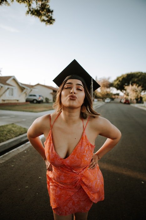 Woman with a graduation cap on making a kissy face with her eyes closed