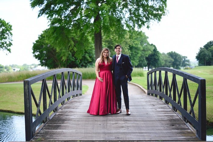 A couple formally dressed up and standing on a small bridge