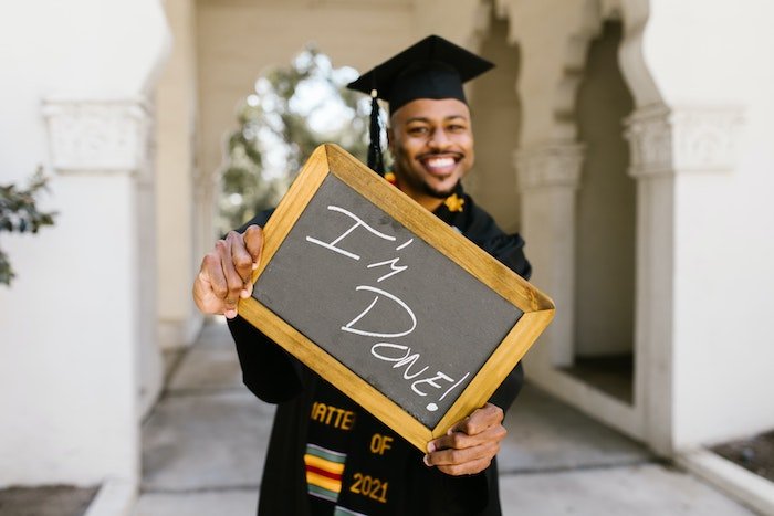 Senior high-school graduate posing with a mini chalkboard with writing "I'm Done!" as a fun senior picture idea