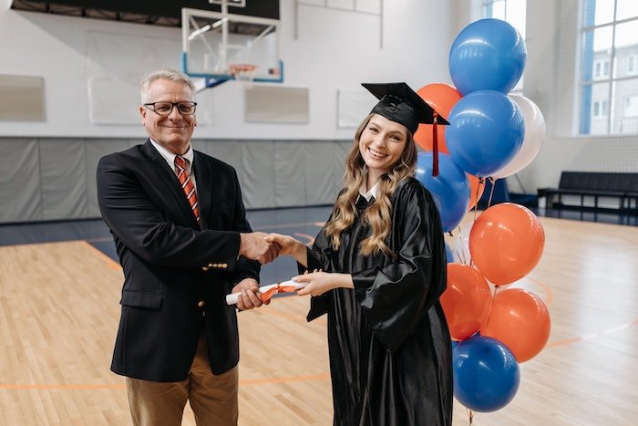 Senior high-school graduate receiving their diploma from a teaching and shaking their hand