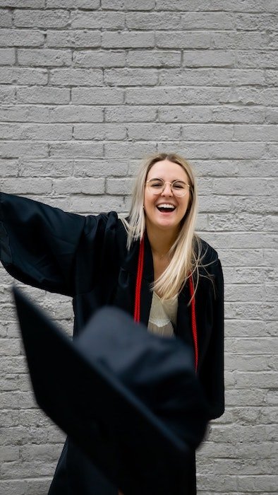 Senior high-school graduate throwing a cap at the photographer