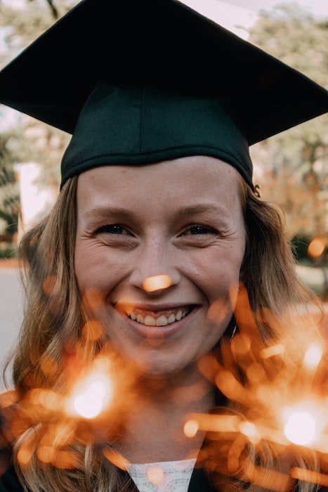 Close-up portrait of a señor high-school graduate with sparklers as a unique senior picture idea