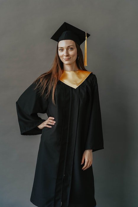 Studio portrait of a graduate posing in a black gown and cap