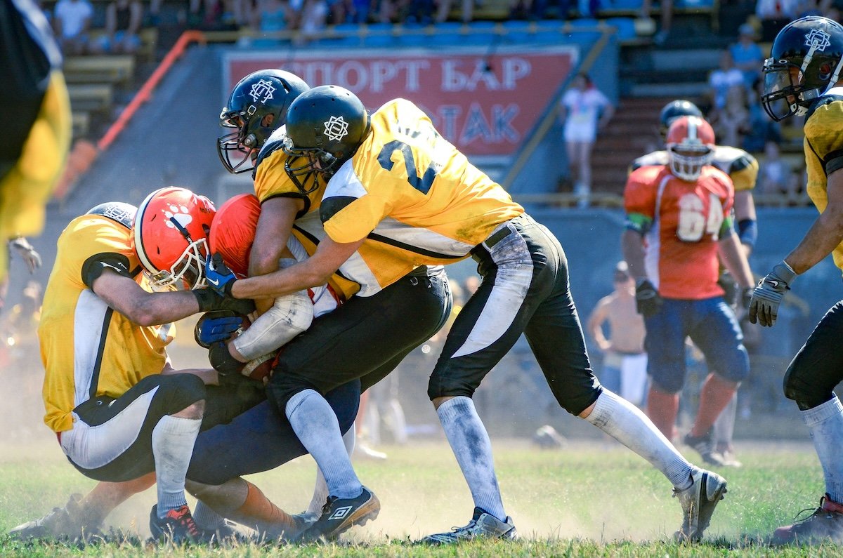 American football players in a scrum on a field in a game as an example of sports photography settings