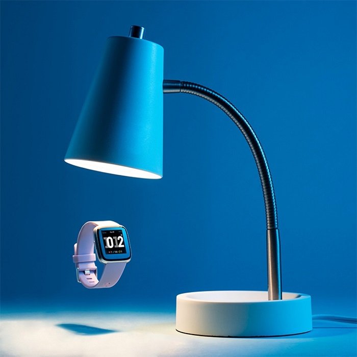 A blue lamp shining light on a floating watch
