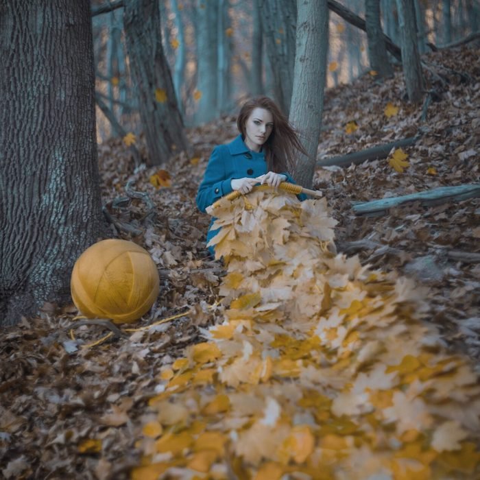 A conceptual fine art photo of a woman sweing leaves in a forest
