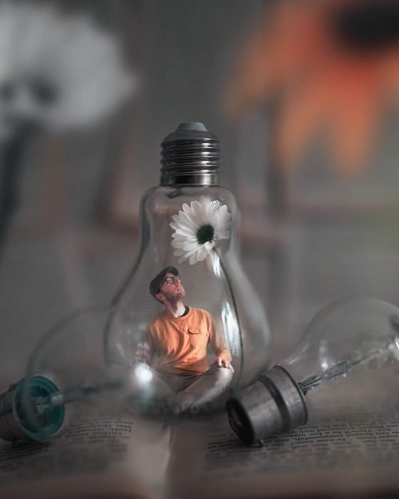 A composite Photoshopped image of a man with a white flower inside a lightbulb