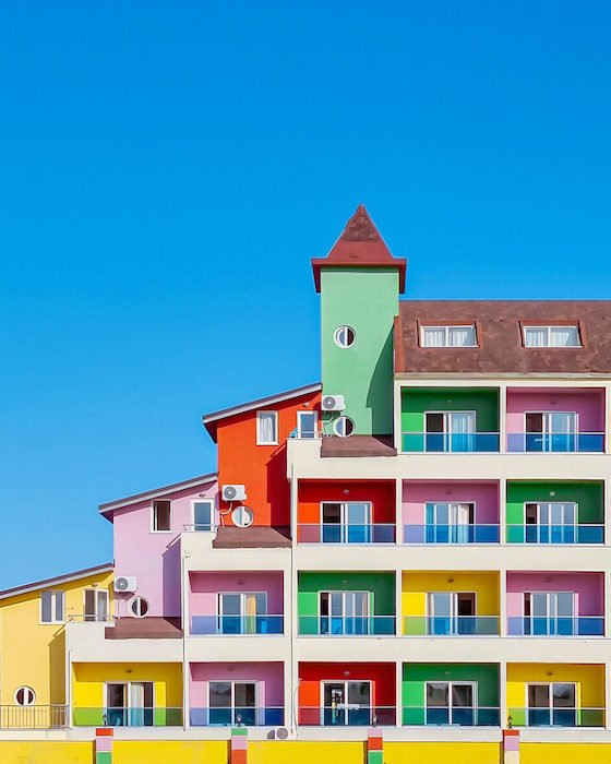 A color building with staggered rooftops, a tower, and balconies