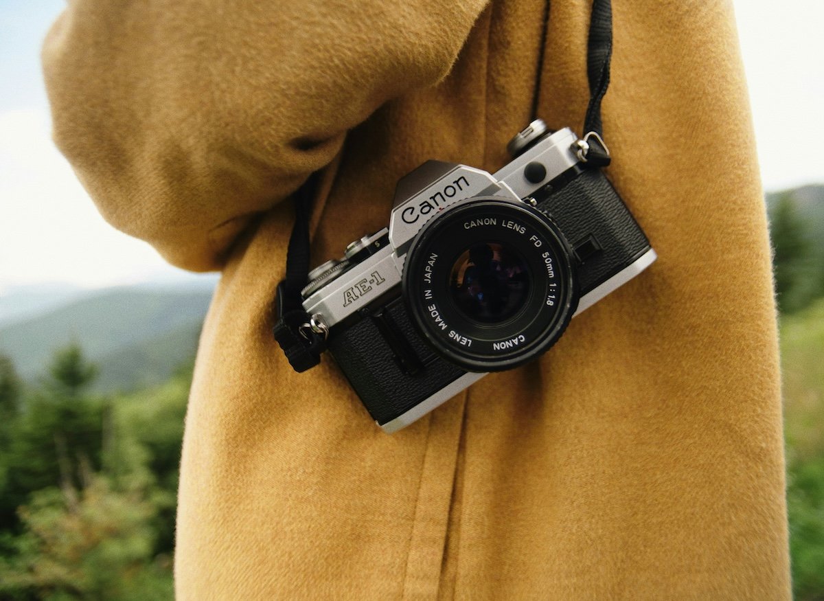 A Canon AE-1 film camera being carried