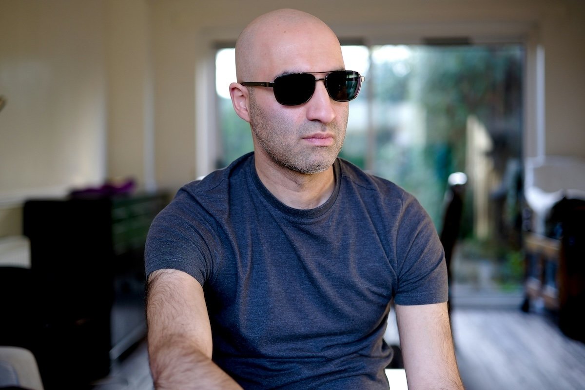 Indoor portrait of a bald man wearing sunglass shot with a wide aperture of f/1.4