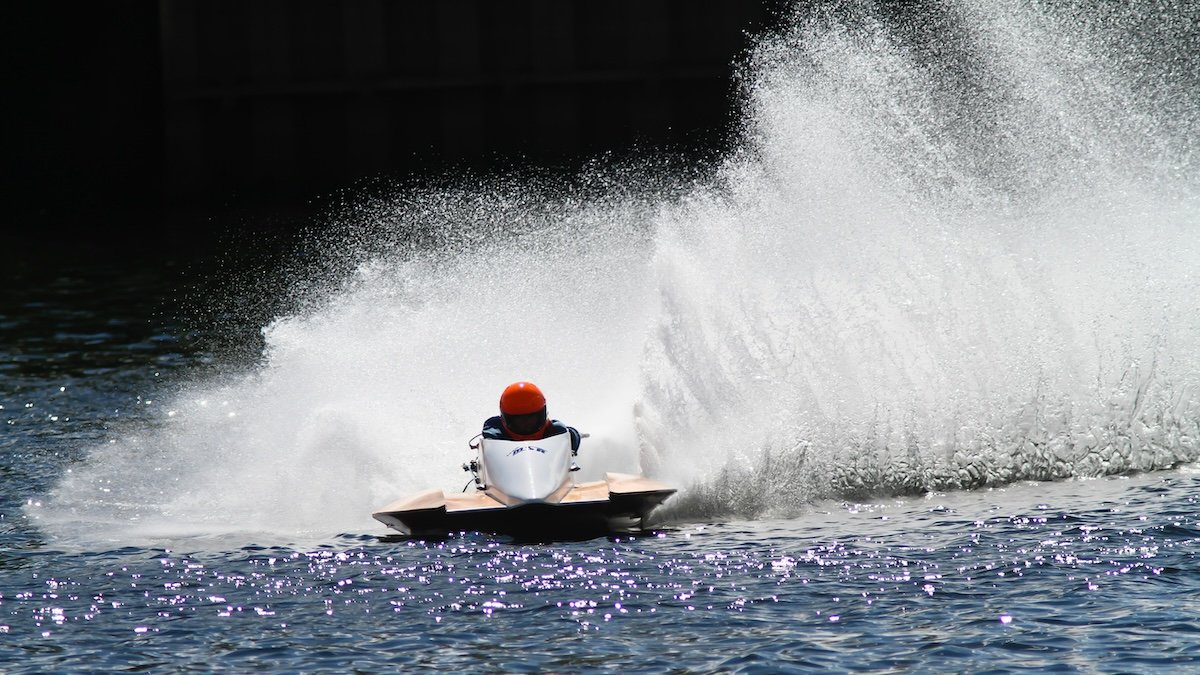 A speedboat racing with water flying up beside it shot with an f/5.6 aperture