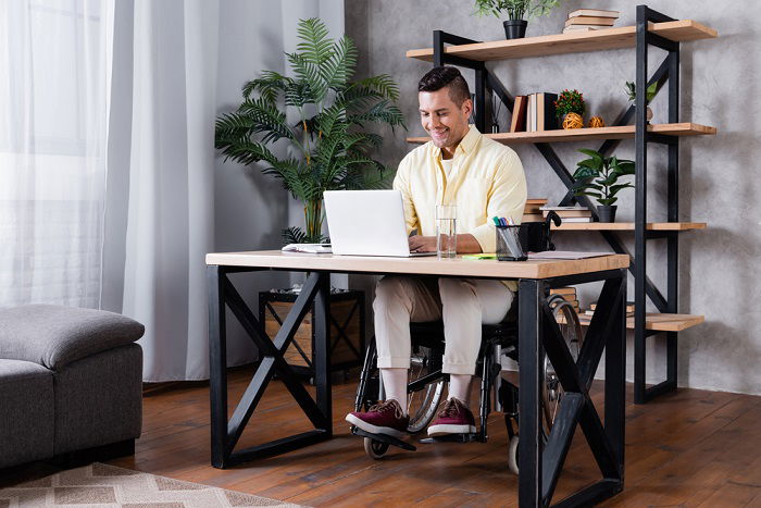 Man in a wheelchair working at a desk at home