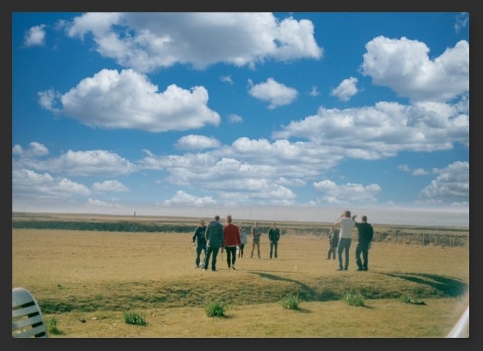 Foto de pessoas em um campo perto do mar, mas o céu foi substituído