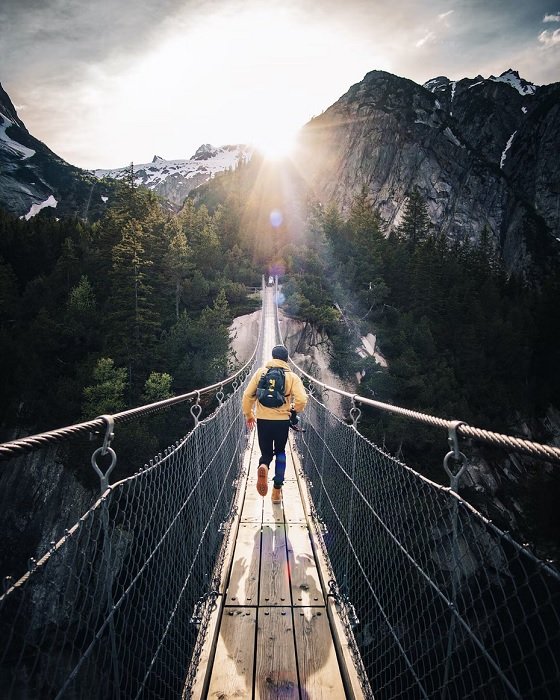 Man running across a mountain rope bridge
