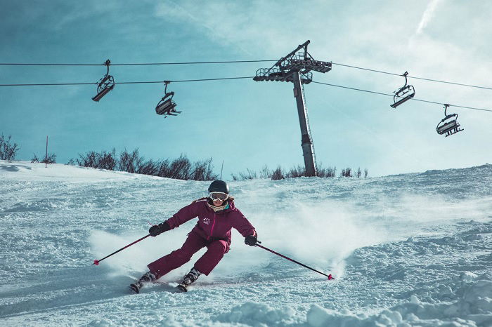 Woman in purple ski suit skiing down a slope