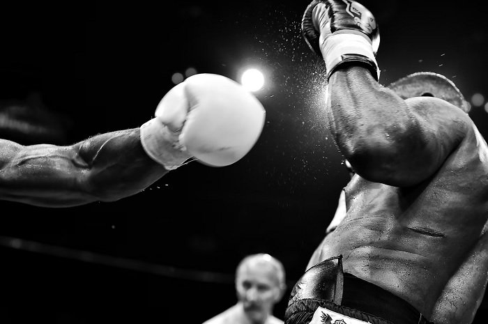 Arm with a boxing glove striking forth at another boxer