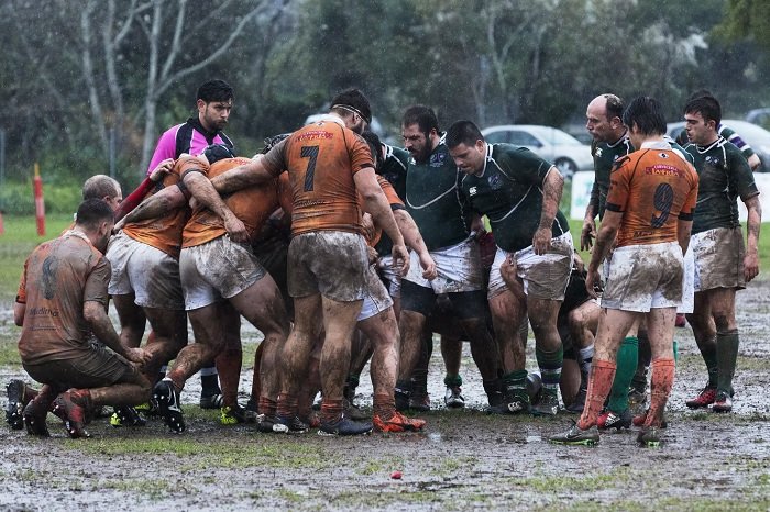 Two packs of forwards preparing of a scrum in a rainy game of rugby