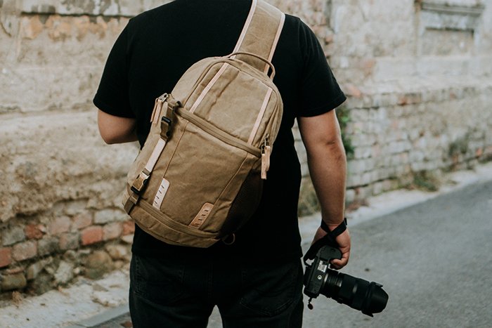 Photographer carrying a camera and a a camera sling bag