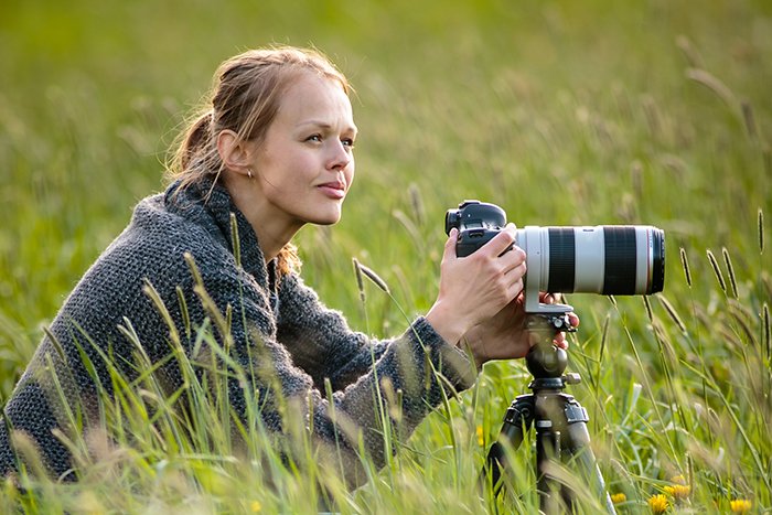 woman photographer with camera on tripod in grass