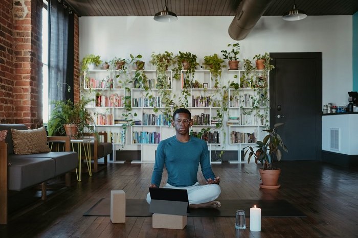 Man meditating at home with an ipad in front of him