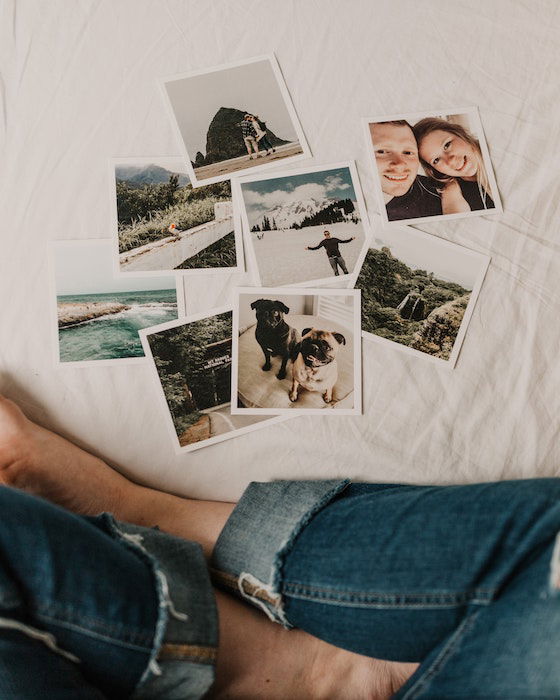 Fotos brilhantes impressas em formato quadrado exibidas na frente de uma pessoa sentada em uma cama