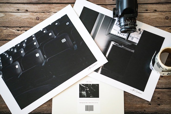 Flat lay of black and white lustre print photographs and a camera on a table
