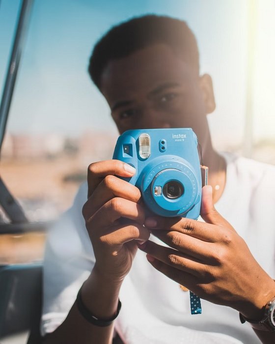 Young man in white tshirt holding an instax mini camera
