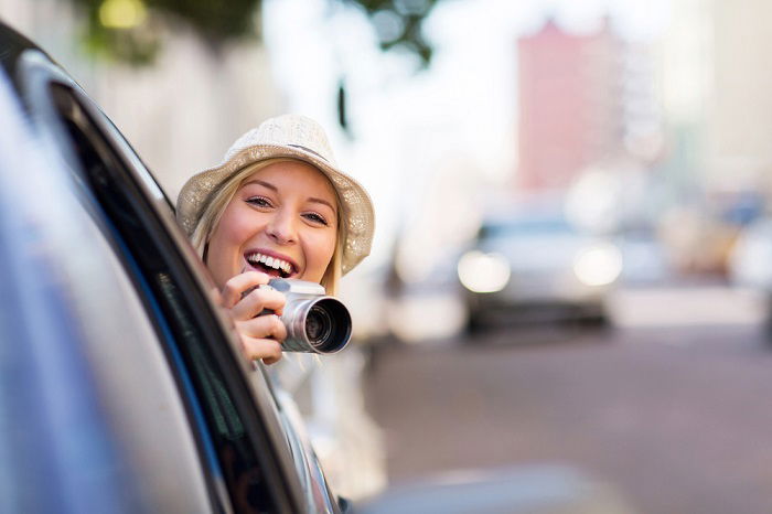 Woman holding a camera out of car window