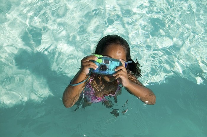 一个小女孩在游泳池里使用防水相机
